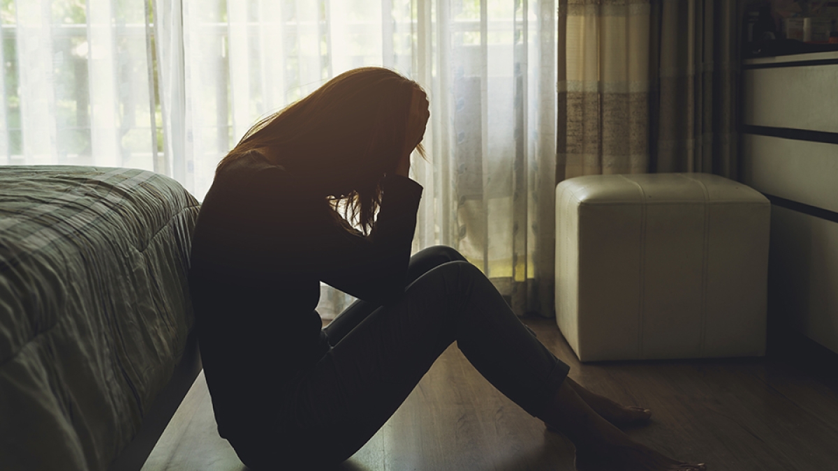 depressed woman sitting head in hands in the dark bedroom